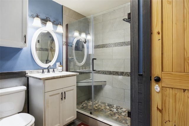 full bathroom featuring toilet, a stall shower, and vanity