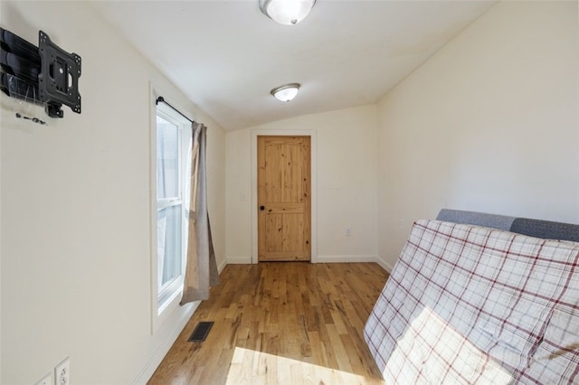 entryway featuring lofted ceiling, baseboards, visible vents, and light wood finished floors