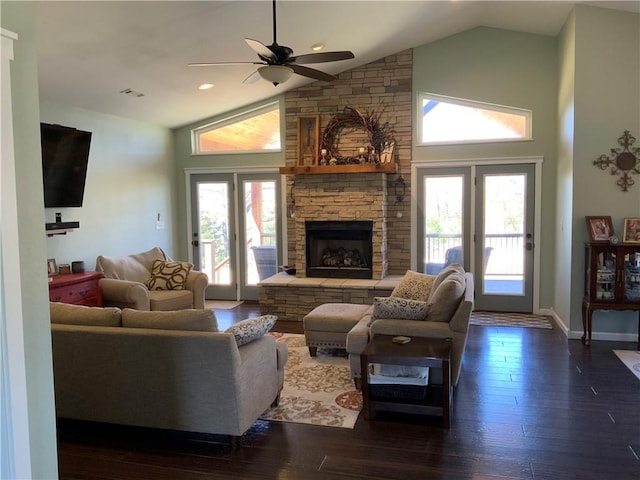 living room with high vaulted ceiling, a ceiling fan, a stone fireplace, baseboards, and dark wood-style flooring