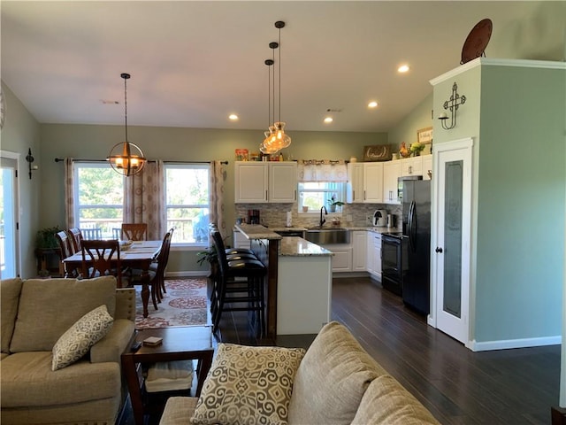 kitchen featuring black appliances, tasteful backsplash, dark wood finished floors, open floor plan, and white cabinets