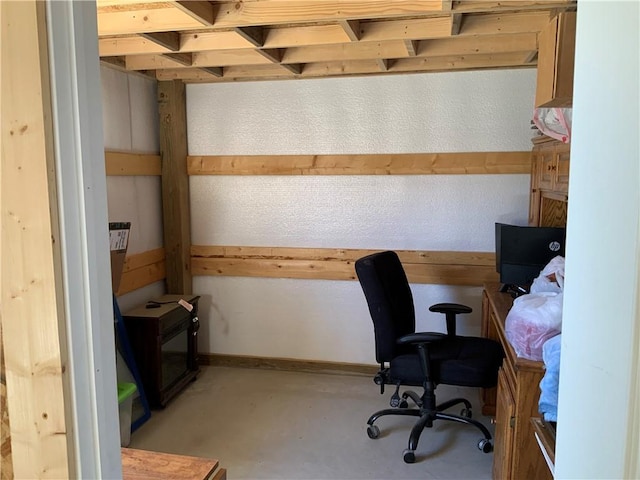 home office featuring baseboards and concrete flooring