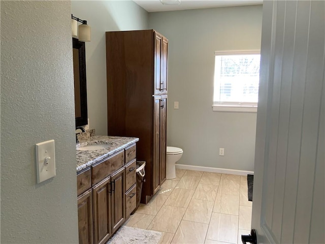 bathroom with toilet, vanity, and baseboards