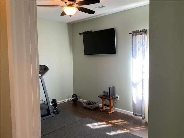 exercise area with visible vents, baseboards, dark wood-style floors, and a ceiling fan