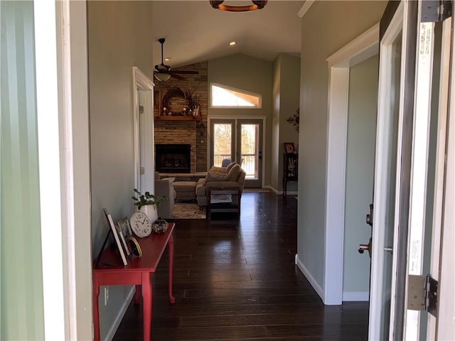 hallway with dark wood finished floors, high vaulted ceiling, and baseboards