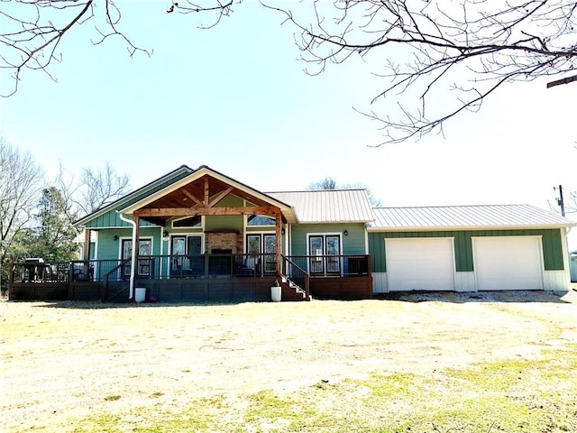 view of front of house featuring board and batten siding, dirt driveway, metal roof, an attached garage, and a standing seam roof