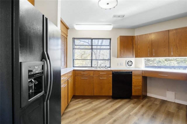 kitchen with plenty of natural light, black appliances, light wood-style flooring, and light countertops