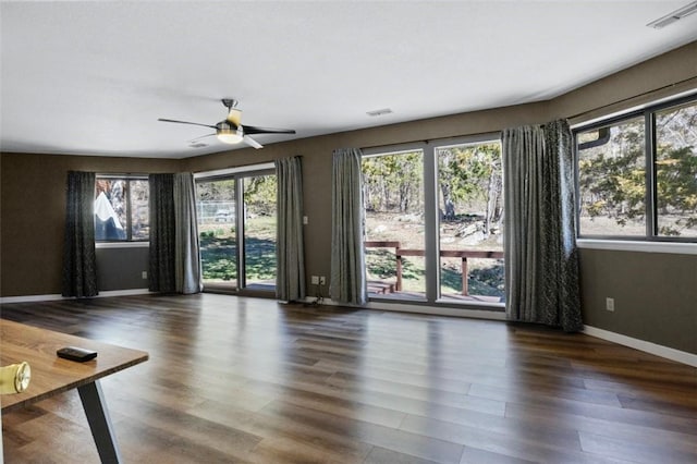 unfurnished living room featuring a ceiling fan, wood finished floors, visible vents, and baseboards