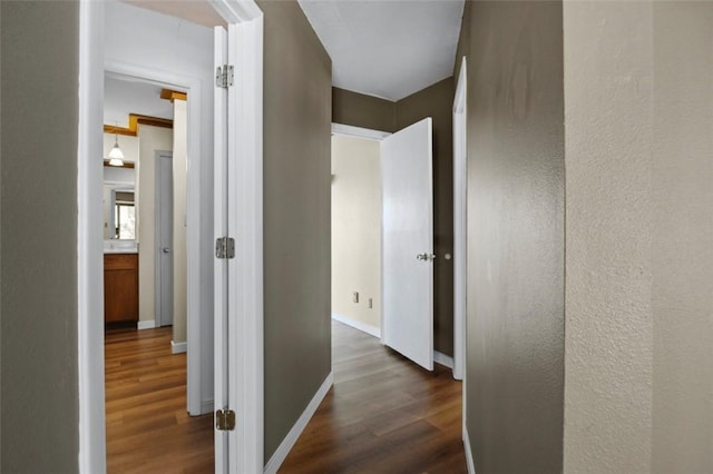 hallway with dark wood finished floors and baseboards