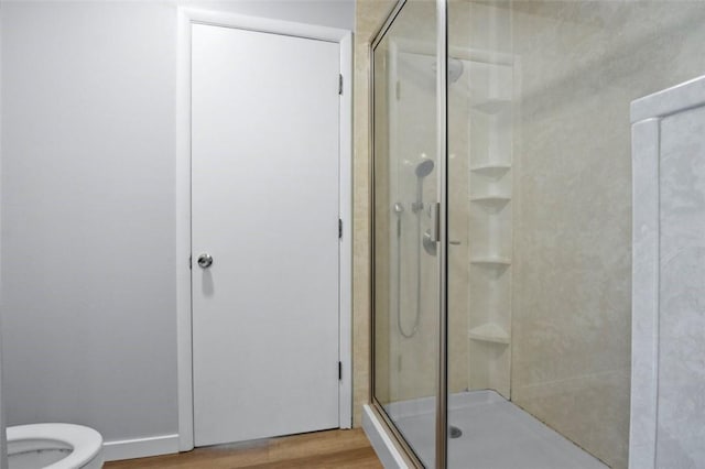 full bath featuring a stall shower, toilet, and wood finished floors