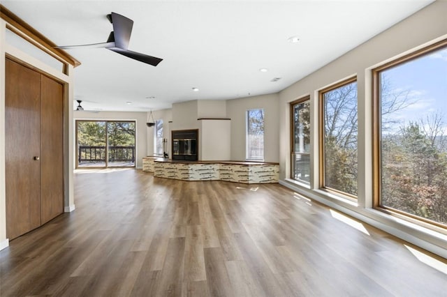 unfurnished living room with a glass covered fireplace, recessed lighting, a ceiling fan, and wood finished floors