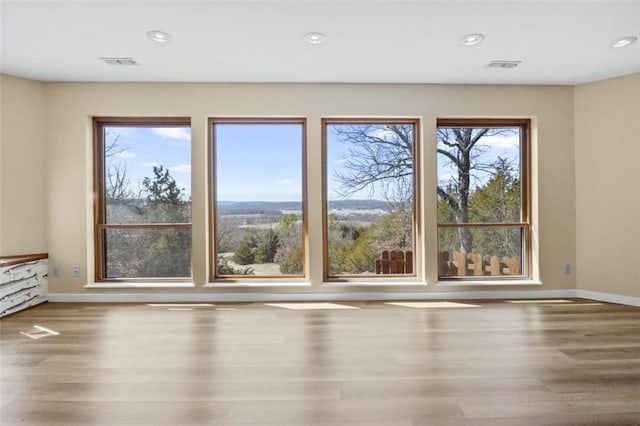 spare room with recessed lighting, baseboards, and wood finished floors