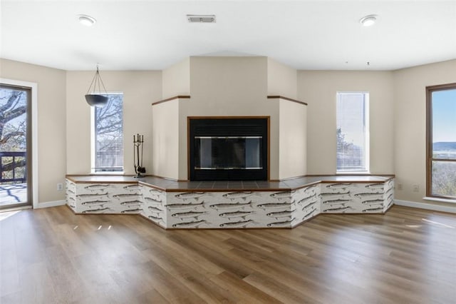 unfurnished living room with a wealth of natural light, visible vents, and wood finished floors