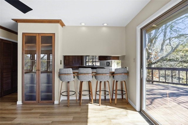 kitchen with recessed lighting, baseboards, a breakfast bar, and wood finished floors