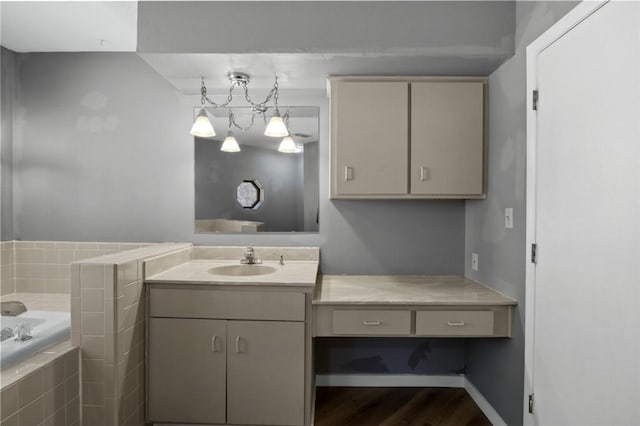 bathroom with baseboards, vanity, a garden tub, and wood finished floors