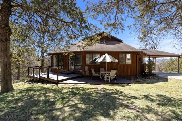 back of property featuring a carport, a lawn, and a wooden deck