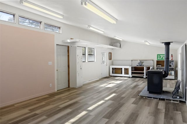 unfurnished living room with a wood stove, wood finished floors, and baseboards