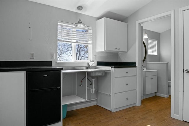 kitchen featuring light wood finished floors, white cabinetry, dark countertops, and a wealth of natural light