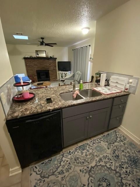 kitchen with ceiling fan, gray cabinetry, a sink, black dishwasher, and a brick fireplace