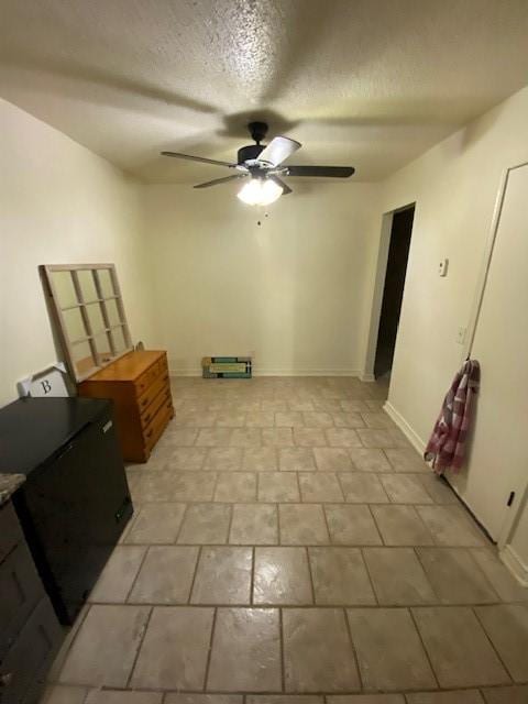 interior space with baseboards, a textured ceiling, and ceiling fan