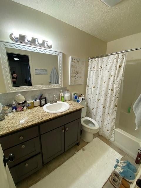 bathroom featuring shower / bath combo with shower curtain, a textured ceiling, vanity, and toilet