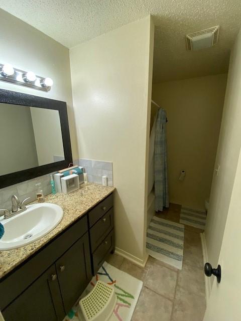 full bathroom with tile patterned flooring, visible vents, vanity, shower / tub combo with curtain, and a textured ceiling