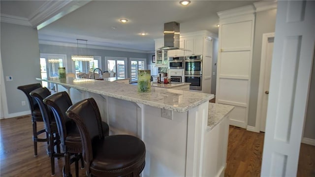 kitchen with double oven, ventilation hood, crown molding, and white cabinets