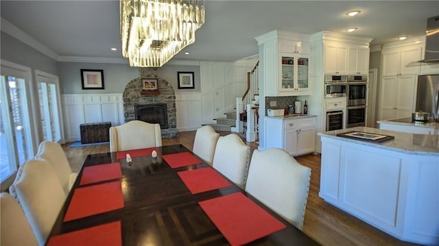 19 Razorback Rd, Rogers, AR 72758 - dining space featuring stairway, a fireplace, ornamental molding, a decorative wall, and a chandelier