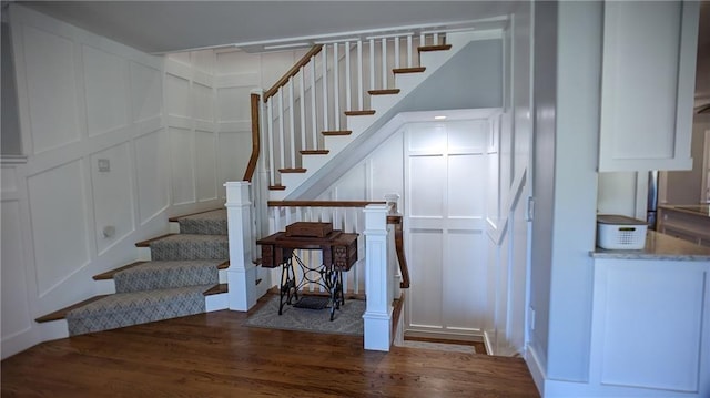 staircase featuring wood finished floors and a decorative wall