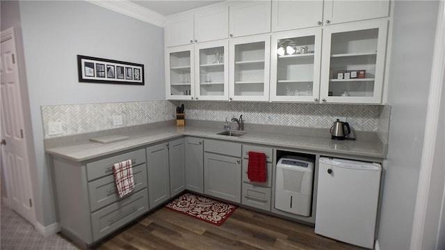 kitchen with gray cabinetry, backsplash, refrigerator, light countertops, and glass insert cabinets