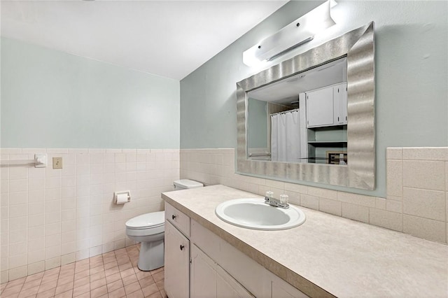 full bath featuring vanity, wainscoting, tile patterned floors, toilet, and tile walls