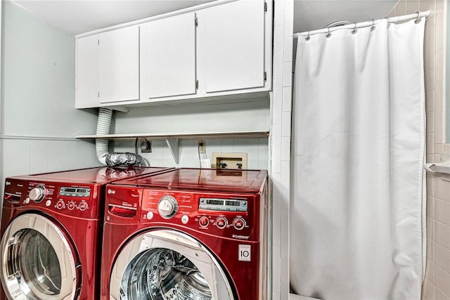 laundry room with a wainscoted wall, washing machine and dryer, and laundry area