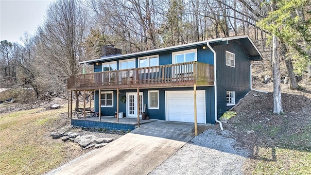 view of front of home featuring french doors, a wooden deck, driveway, and a garage