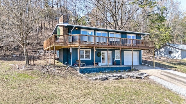 view of front of home featuring an attached garage, french doors, driveway, and a wooden deck