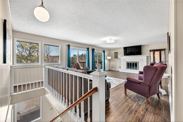 living area with plenty of natural light, a fireplace, a textured ceiling, and wood finished floors