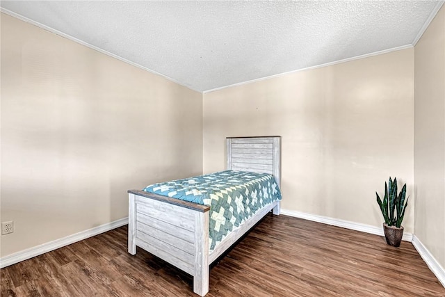 bedroom with ornamental molding, wood finished floors, baseboards, and a textured ceiling