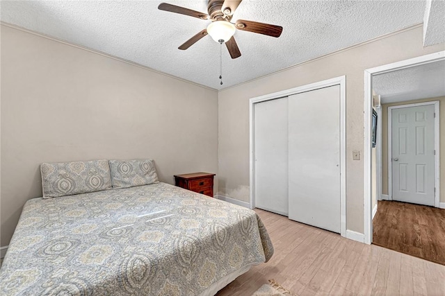 bedroom with baseboards, wood finished floors, a closet, a textured ceiling, and a ceiling fan