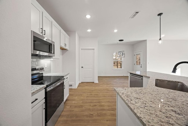 kitchen with visible vents, backsplash, white cabinets, stainless steel appliances, and a sink