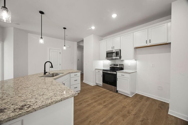 kitchen with tasteful backsplash, stainless steel appliances, wood finished floors, white cabinetry, and a sink