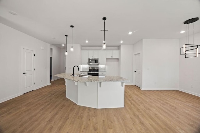 kitchen featuring light wood finished floors, visible vents, stainless steel appliances, white cabinetry, and a sink