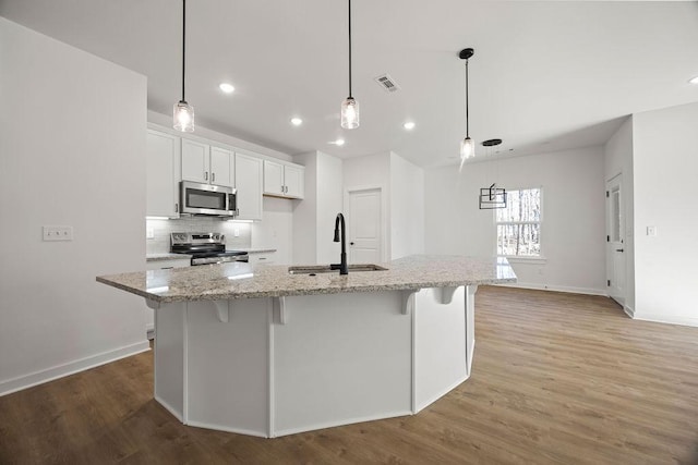 kitchen with a sink, stainless steel appliances, light wood-type flooring, and tasteful backsplash