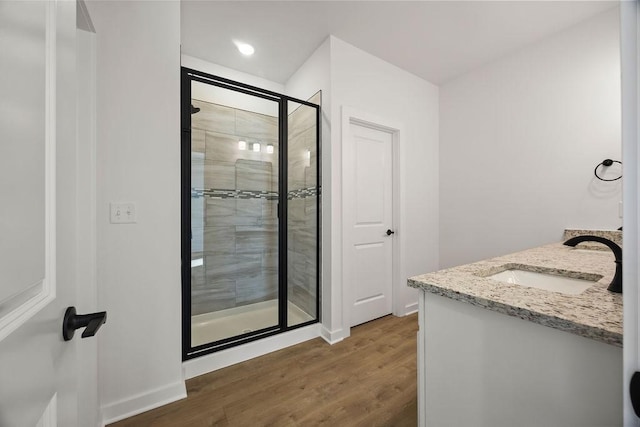 bathroom featuring a shower stall, vanity, baseboards, and wood finished floors