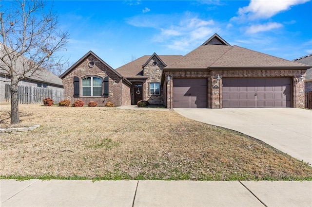 french country style house with concrete driveway, an attached garage, fence, and brick siding