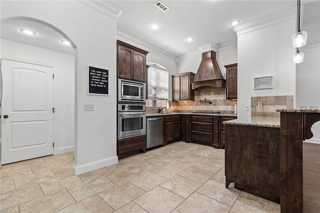 kitchen with premium range hood, visible vents, stainless steel appliances, a peninsula, and dark brown cabinets