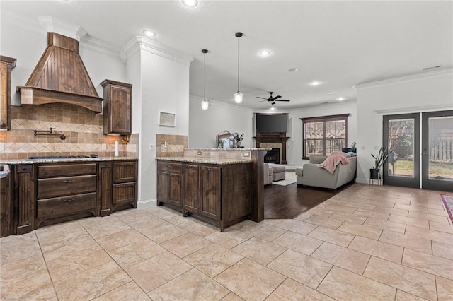 kitchen with a ceiling fan, light stone counters, open floor plan, custom exhaust hood, and dark brown cabinets