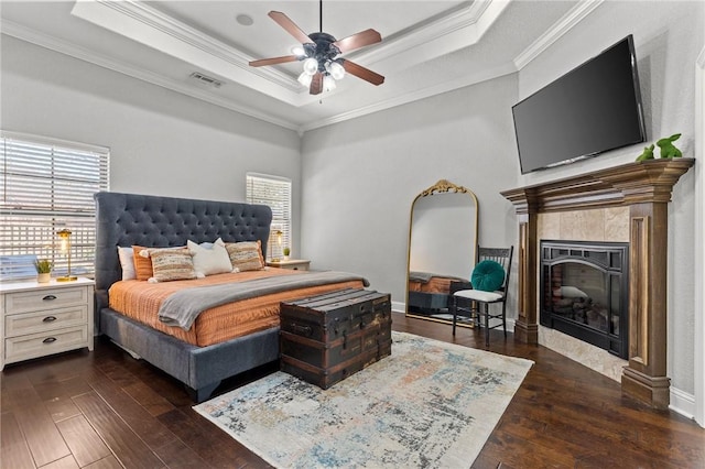 bedroom with dark wood-style floors, visible vents, crown molding, and a tray ceiling