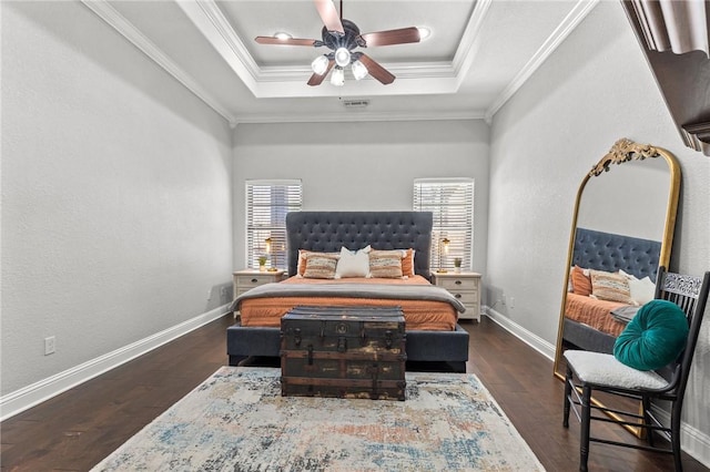 bedroom featuring a ceiling fan, wood finished floors, baseboards, a tray ceiling, and crown molding