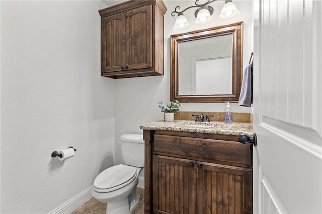 half bath with toilet, vanity, and baseboards