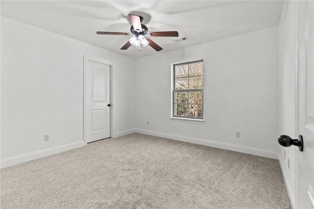 carpeted spare room with visible vents, baseboards, and ceiling fan