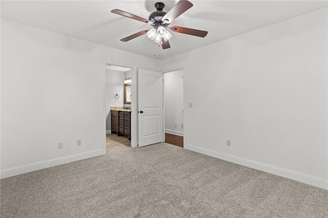 unfurnished bedroom with ceiling fan, baseboards, light carpet, and connected bathroom