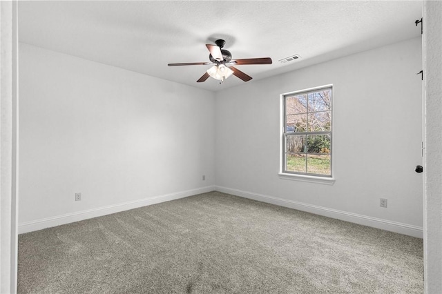 carpeted empty room with visible vents, a textured ceiling, baseboards, and a ceiling fan